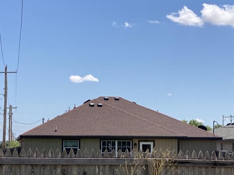 A house with a brown roof and a wooden fence in front of it.