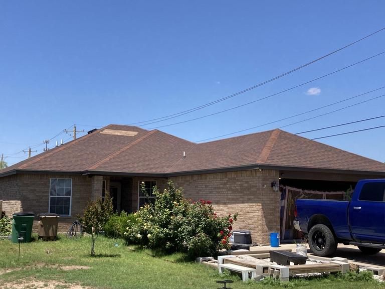 A blue truck is parked in front of a brick house.