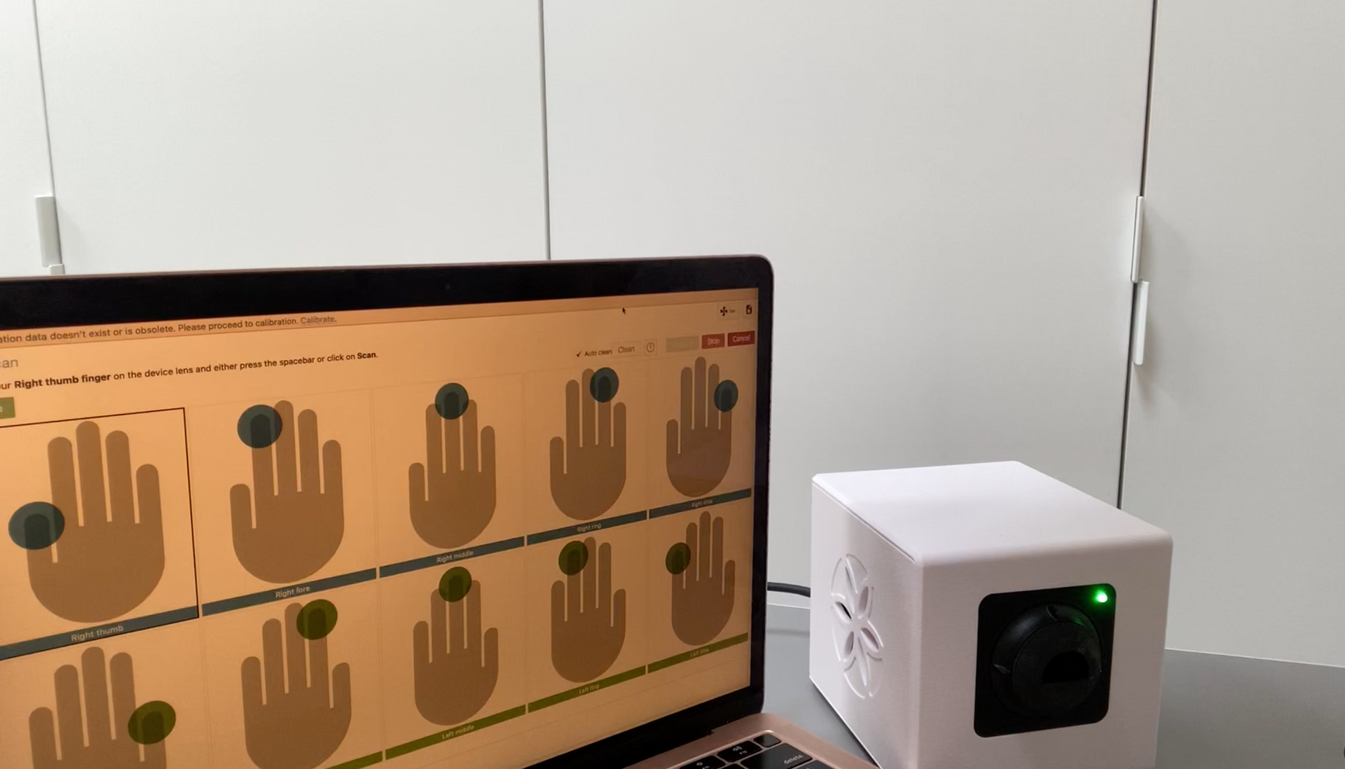 A person presses a finger against a white Bio-Well device. The device has a floral design on the front.