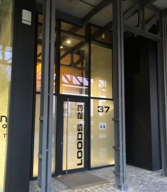 Entrance to LOODS 23, with black frame, glass doors and windows, and a
