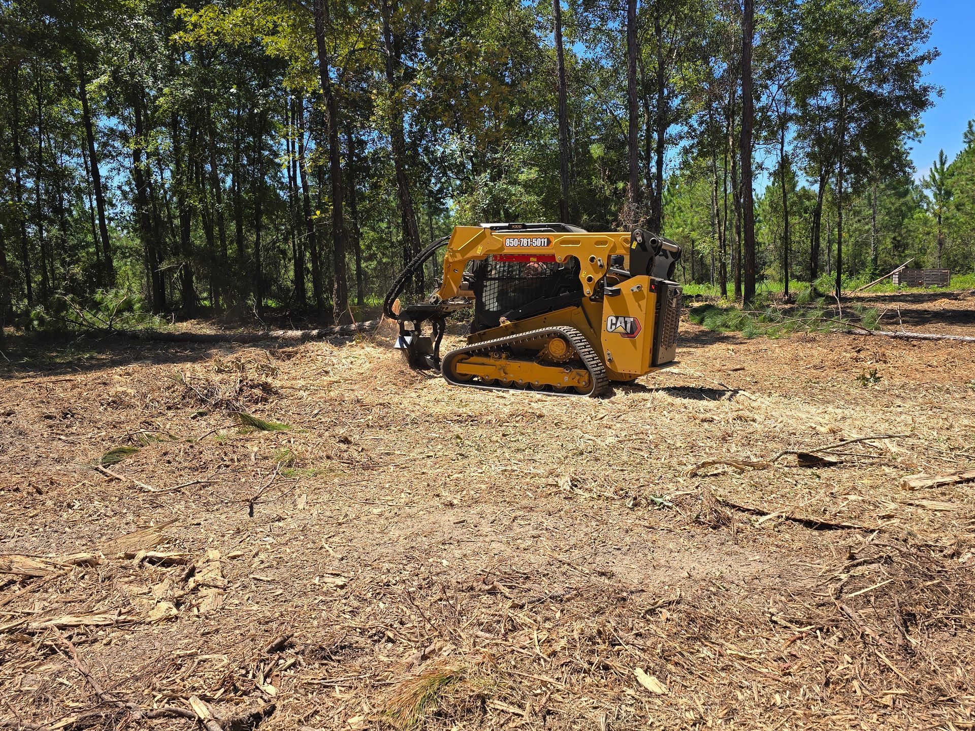 Bobcat excavator digging a trench in a yard, dumping soil onto the ground.