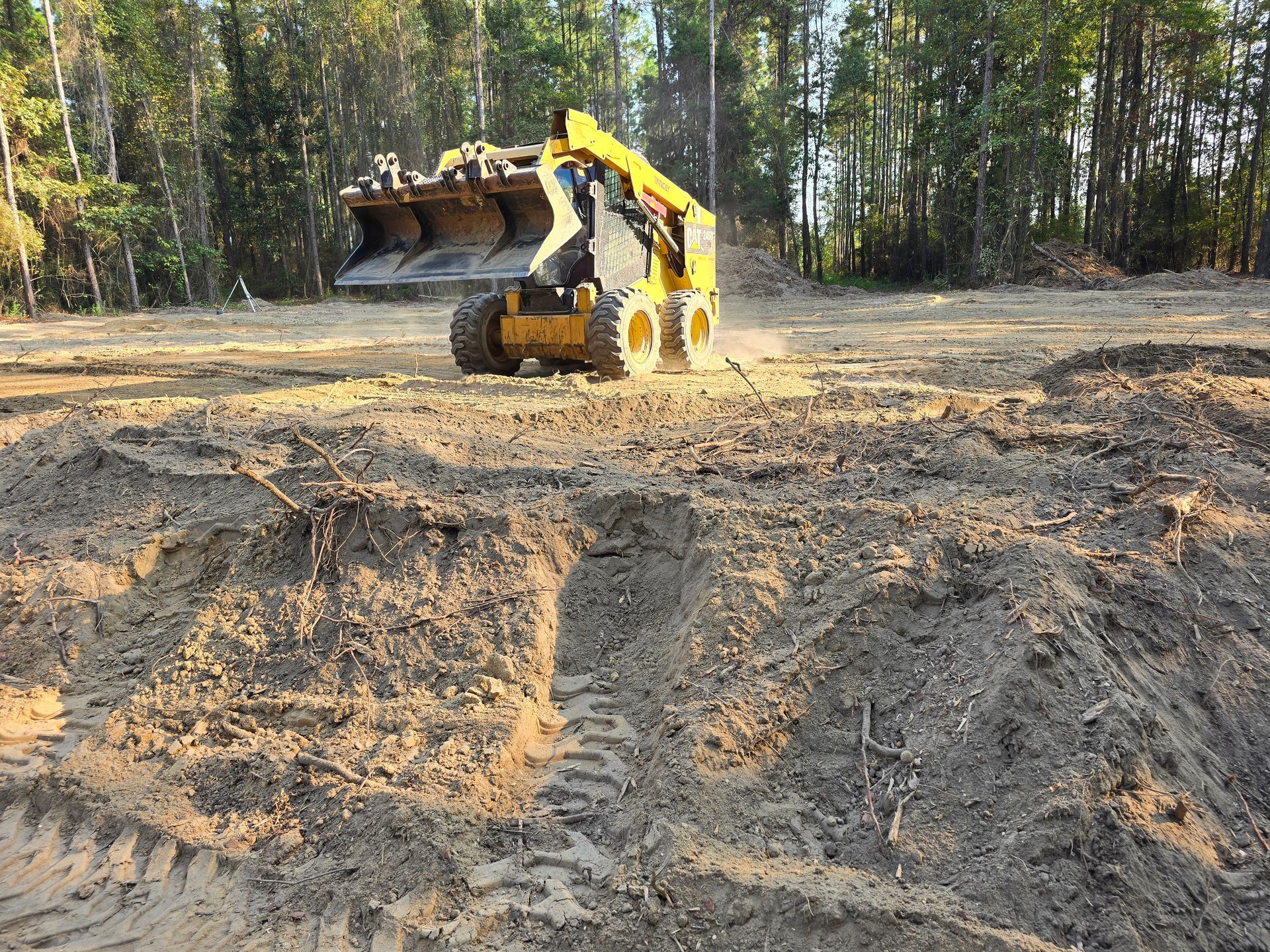 Yellow excavator on tracks; construction site with dirt pile and trees in background.