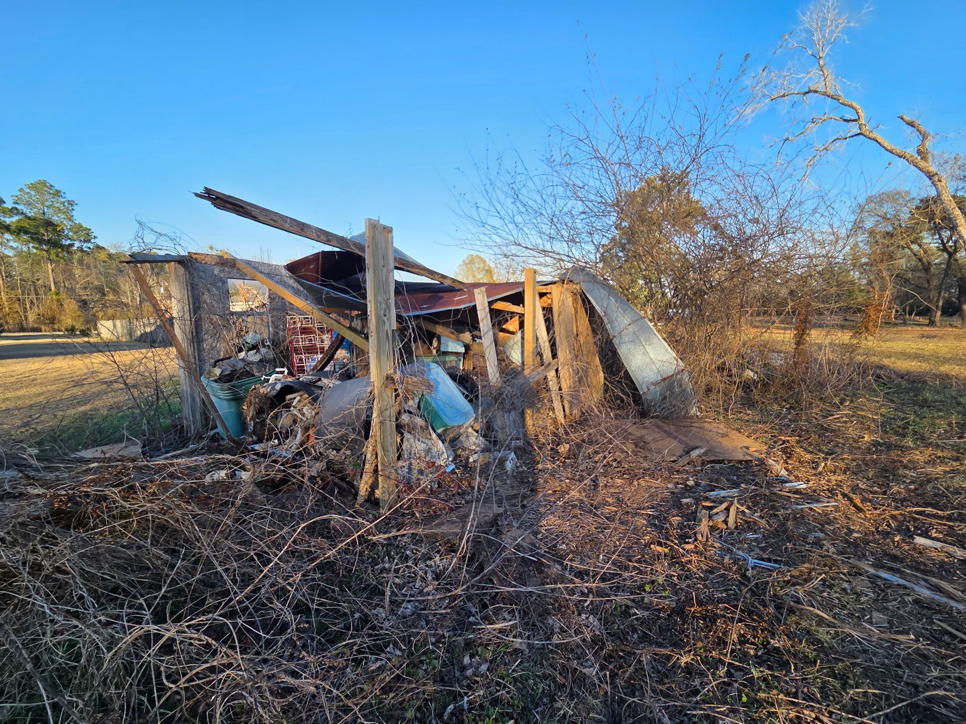 Demolition of a house, excavator loading debris into a truck; brick and wood wreckage.