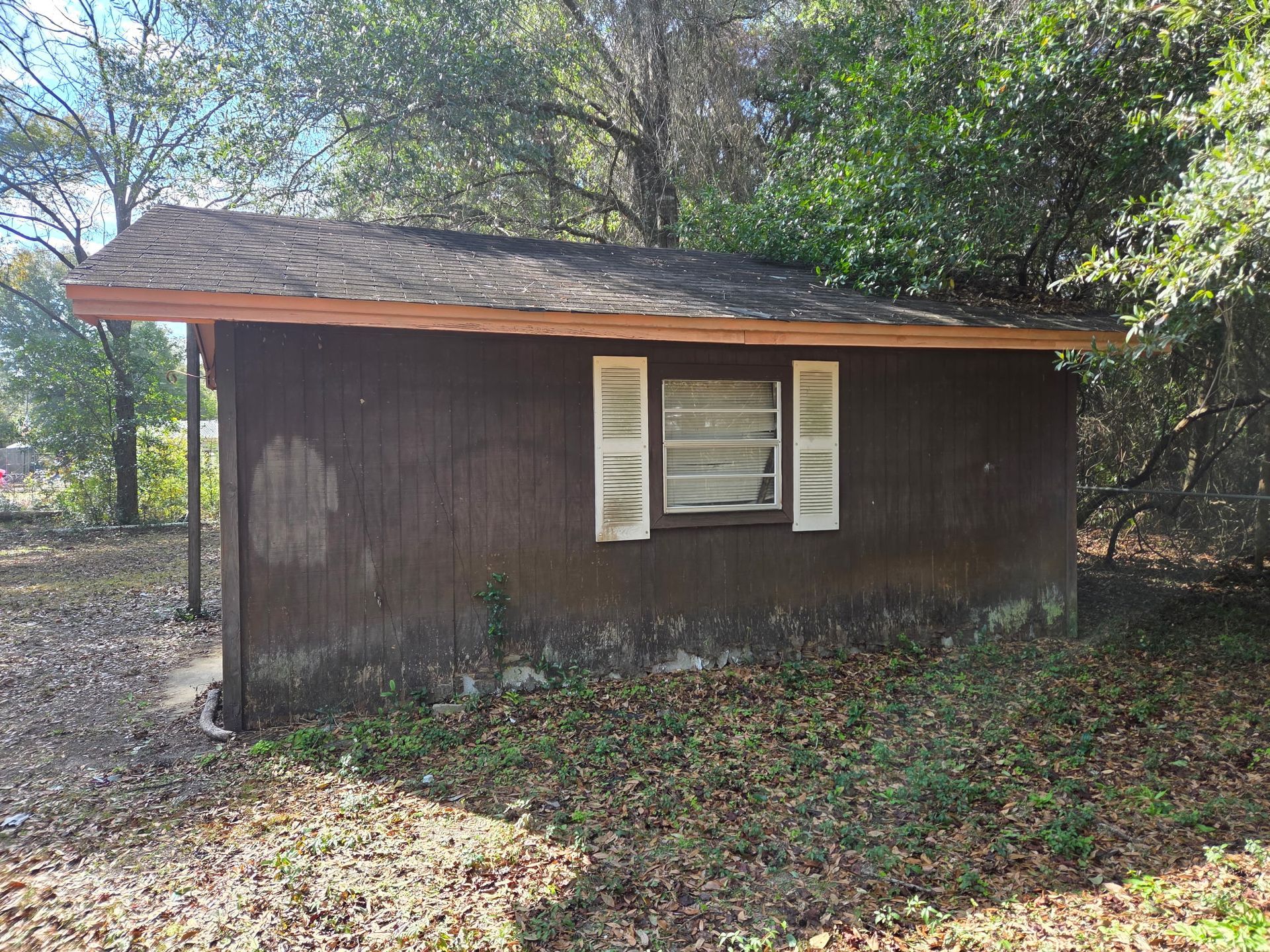 White truck towing a trailer on a dirt road. Trees in the background, daytime.