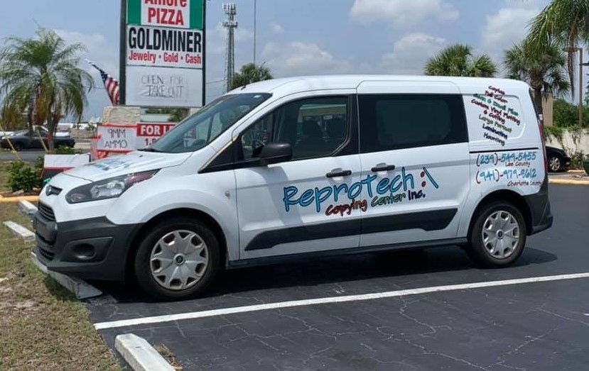 White Reprotech van parked in a lot, with logo on side.  Sign for 