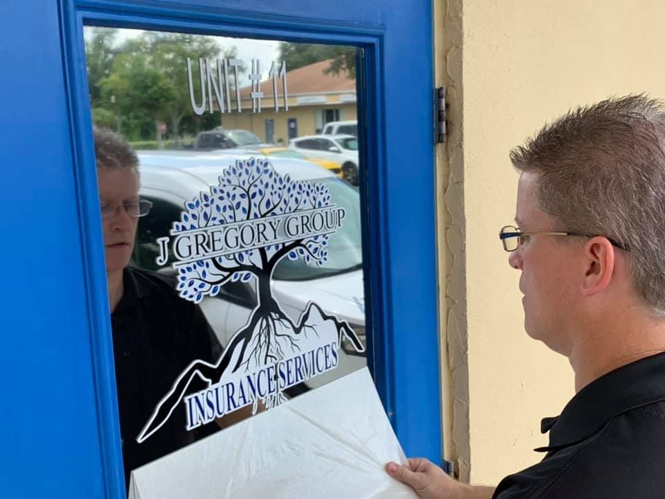 Man applying window decal to a blue door with 