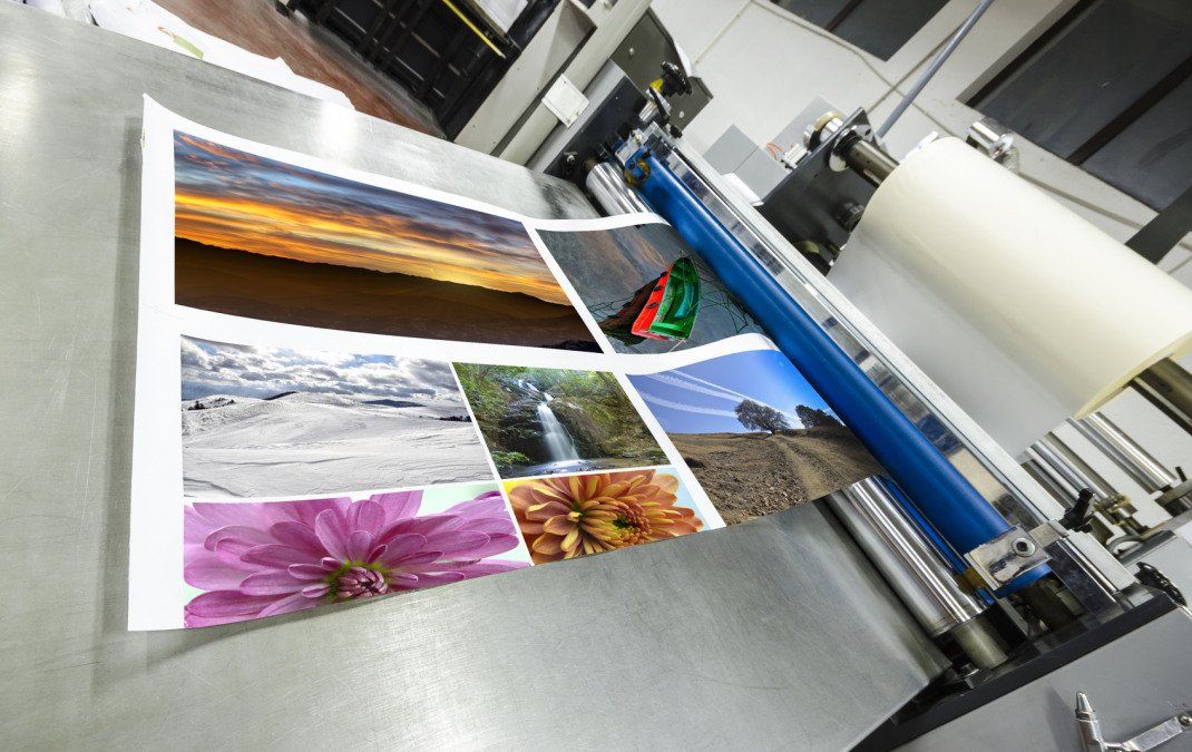 A sheet of photos being laminated by a machine; a roll of clear laminate on the right.