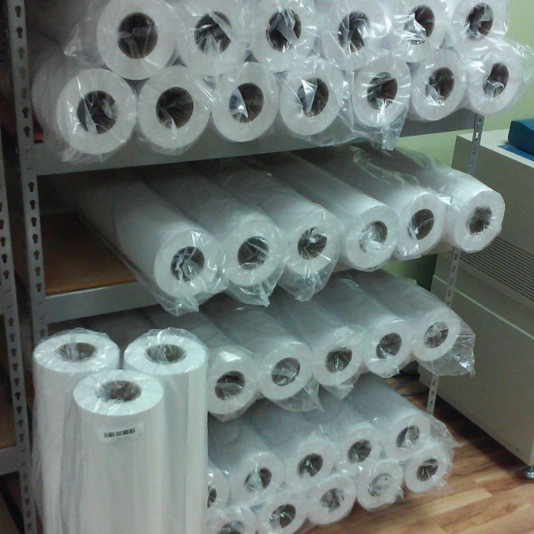 Shelves stacked with rolls of white plastic film, wrapped in clear packaging.