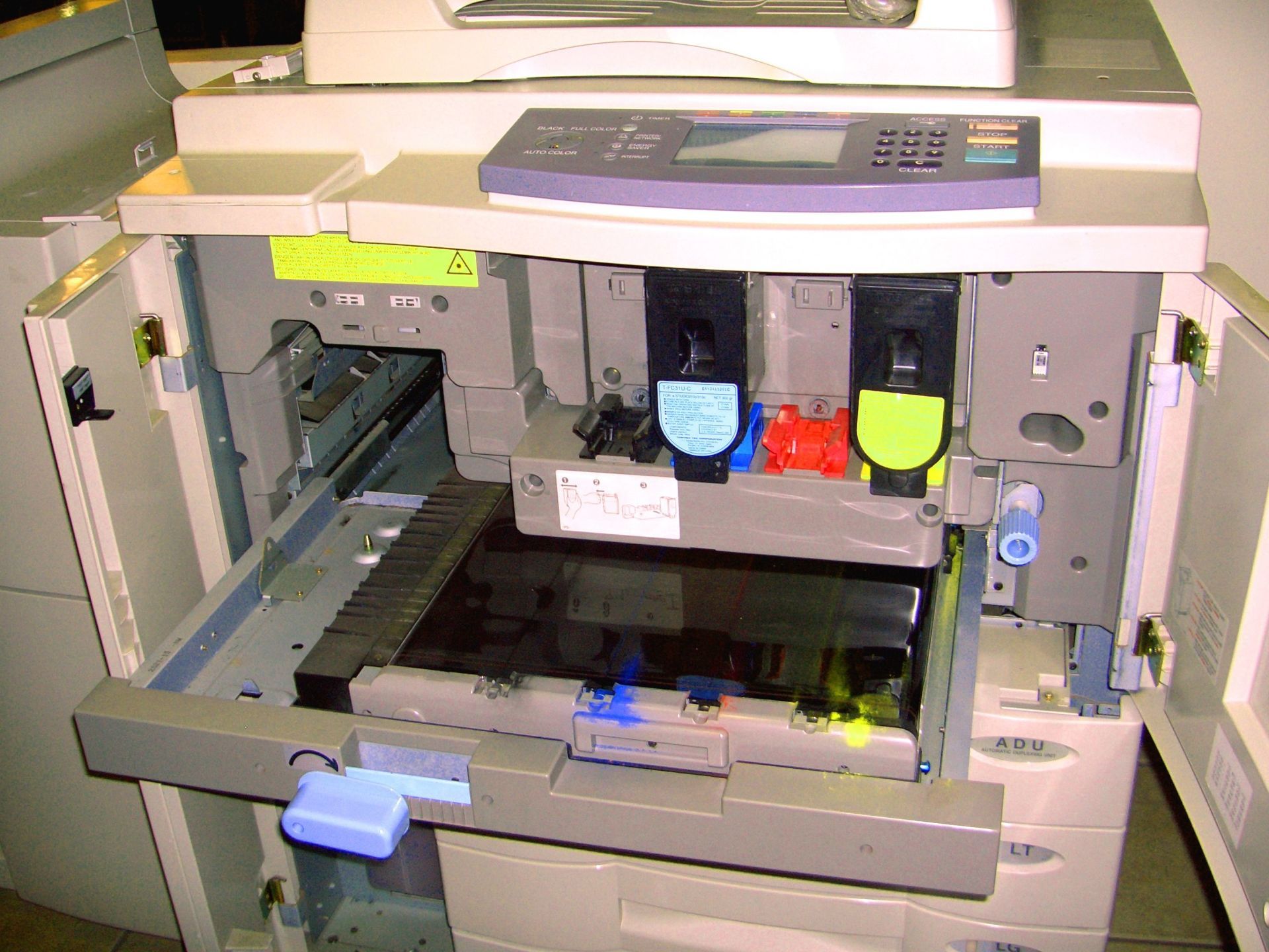Opened office printer, showing cyan, magenta, and yellow ink cartridges.