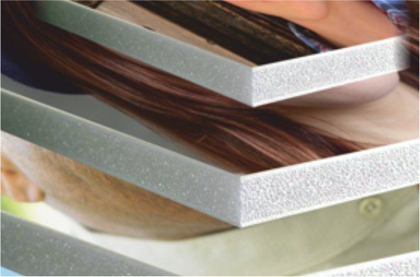 Stack of textured, light gray boards partially obscuring a person with brown hair.