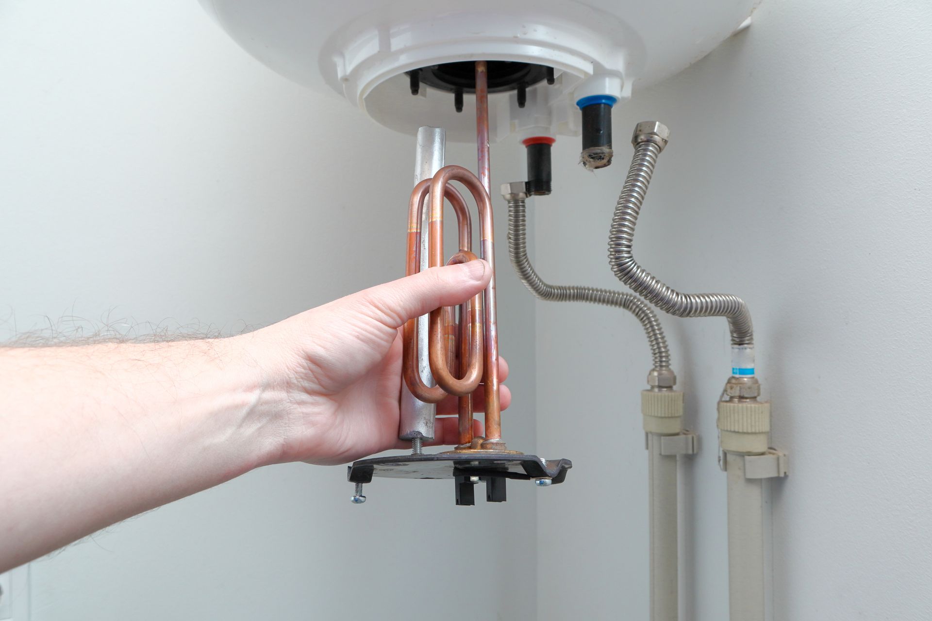 A man's hand putting a new water heater in a boiler. A man's hand putting a new water heater in a boiler.