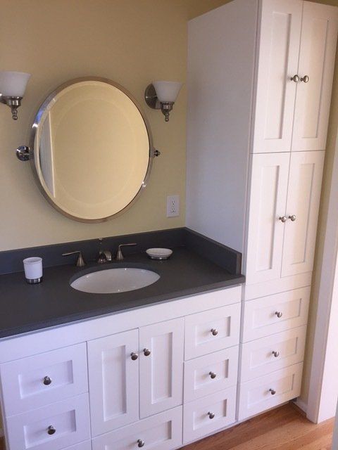 A bathroom with a sink and a round mirror