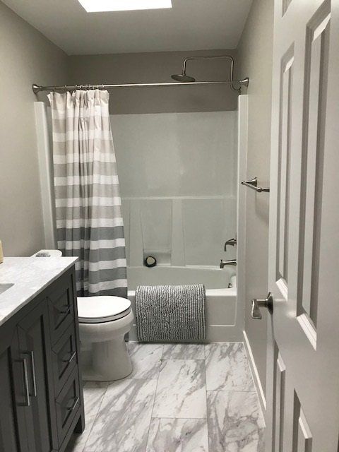 A bathroom with a toilet , sink , bathtub and shower curtain.