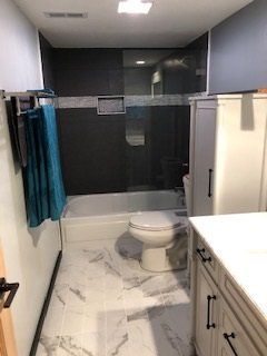 A bathroom with a toilet , tub and shower.