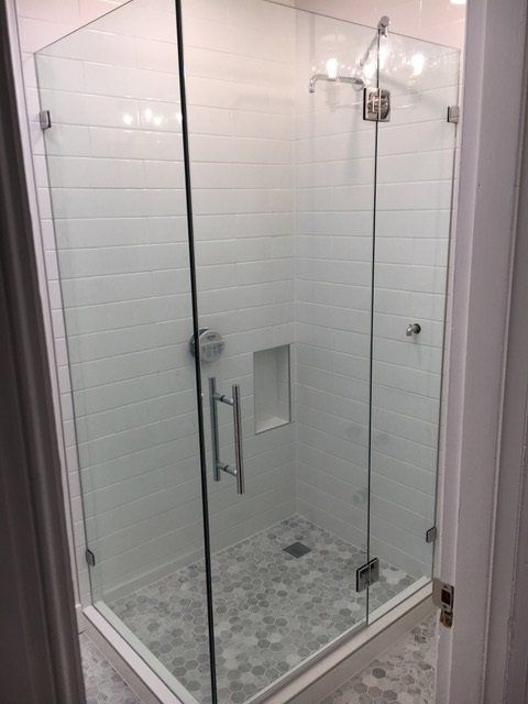 A bathroom with a walk in shower with a glass door.
