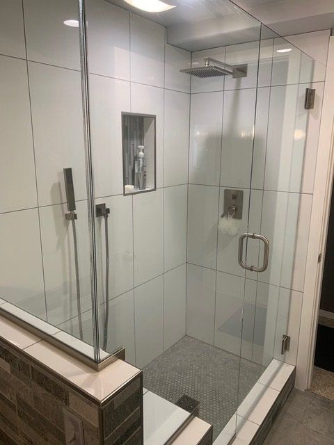 A bathroom with a walk in shower with a glass door.