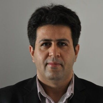 A man in a suit and striped shirt is looking at the camera.