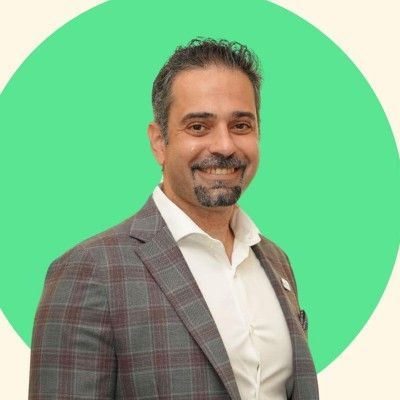 A man with a beard is wearing a suit and smiling.