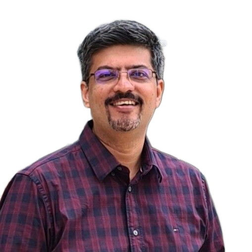 A man in a plaid shirt is sitting at a table in front of a window.