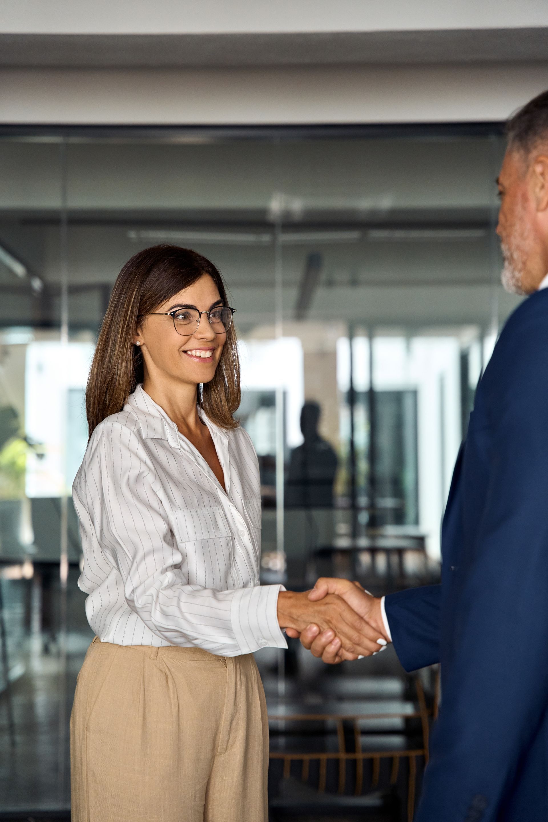 A woman is shaking hands with a man in an office.