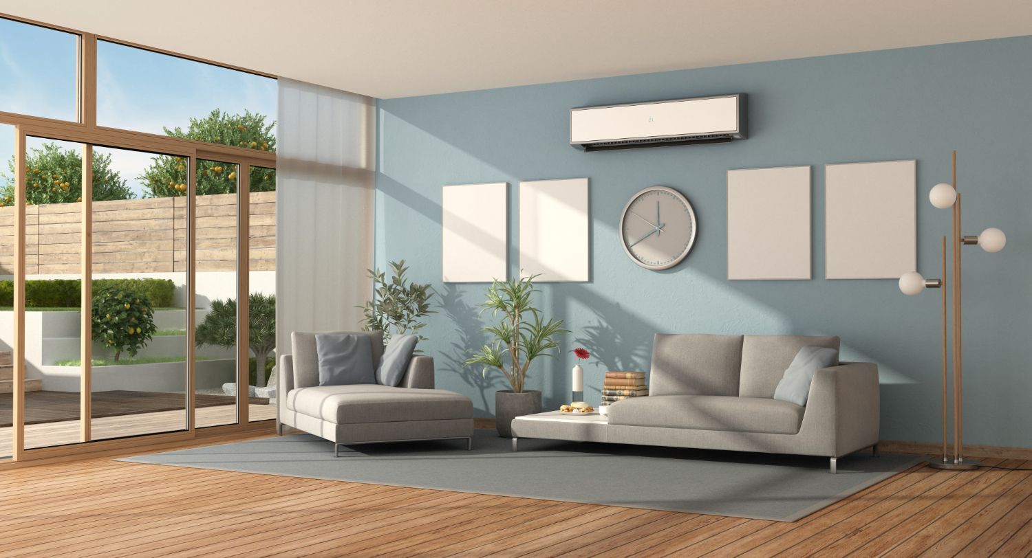 Modern living room with a light gray sofa and chaise, a wall clock, and an air conditioner on a blue wall.