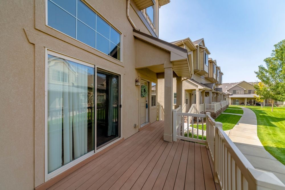 A large deck with a sliding glass door in front of a house.