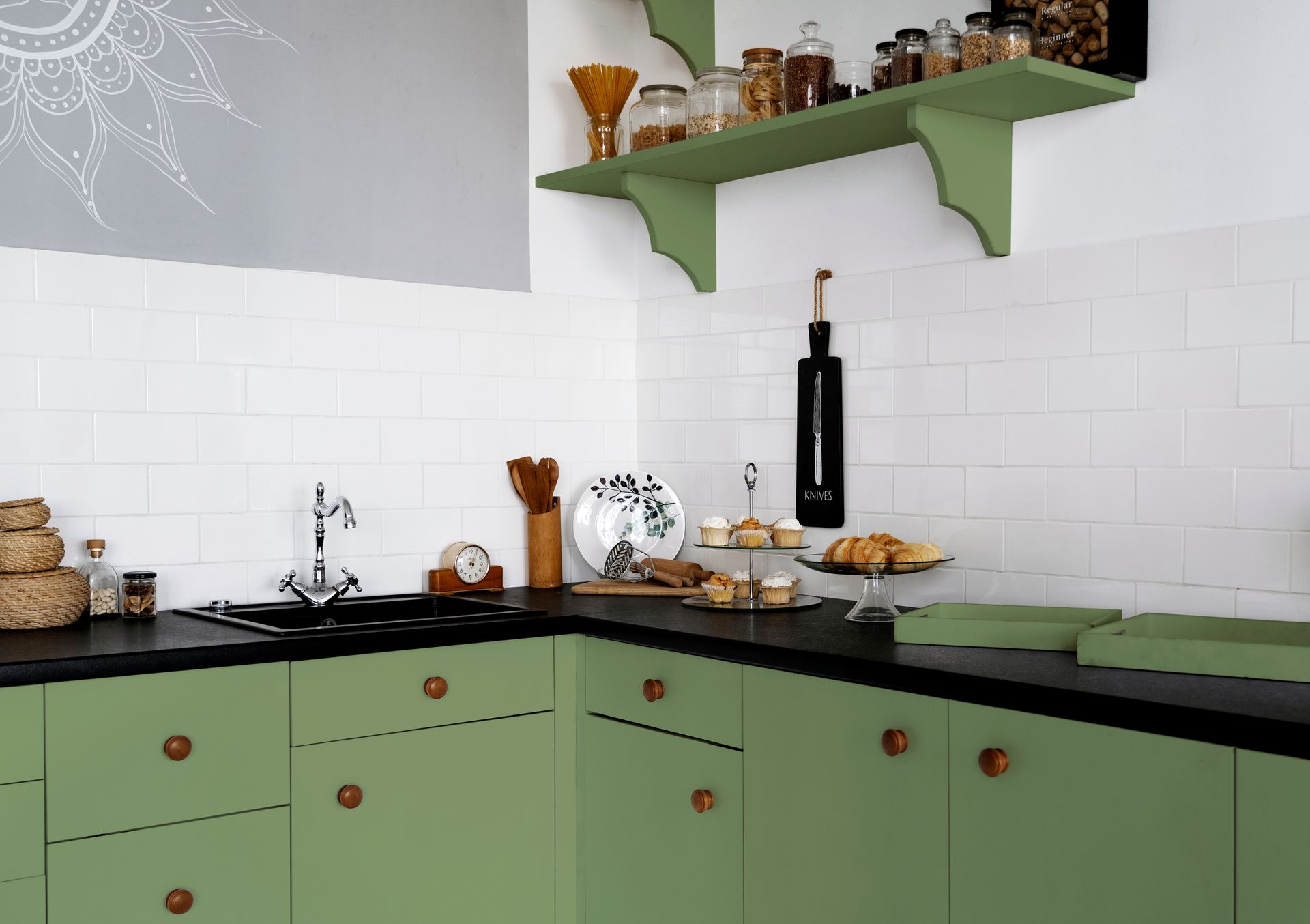 A kitchen with green cabinets and black counter tops