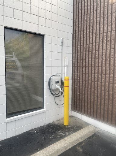 A car charger is attached to the side of a building next to a window.