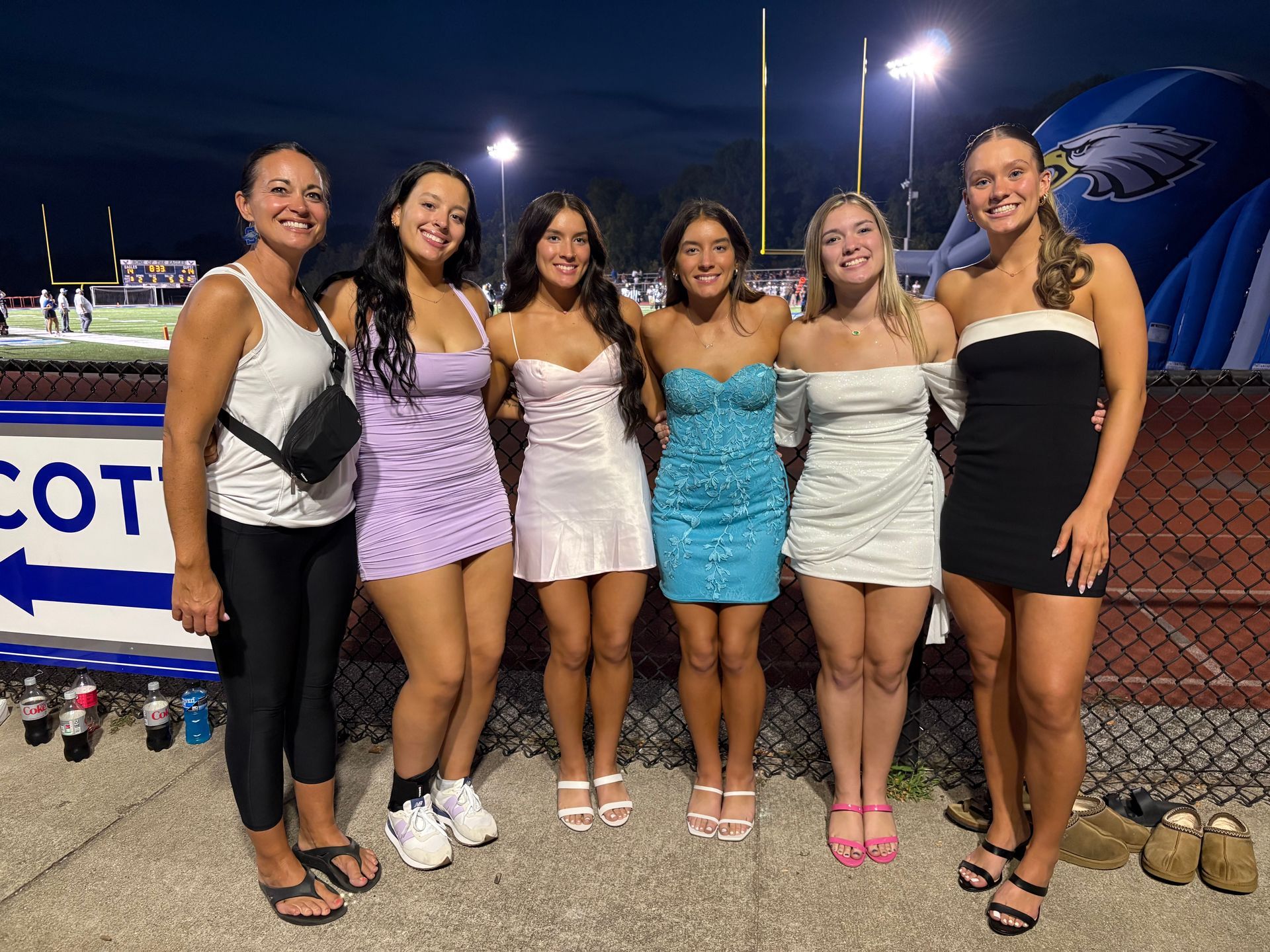 Person spraying another person with a spray gun, next to a backdrop; indoors.