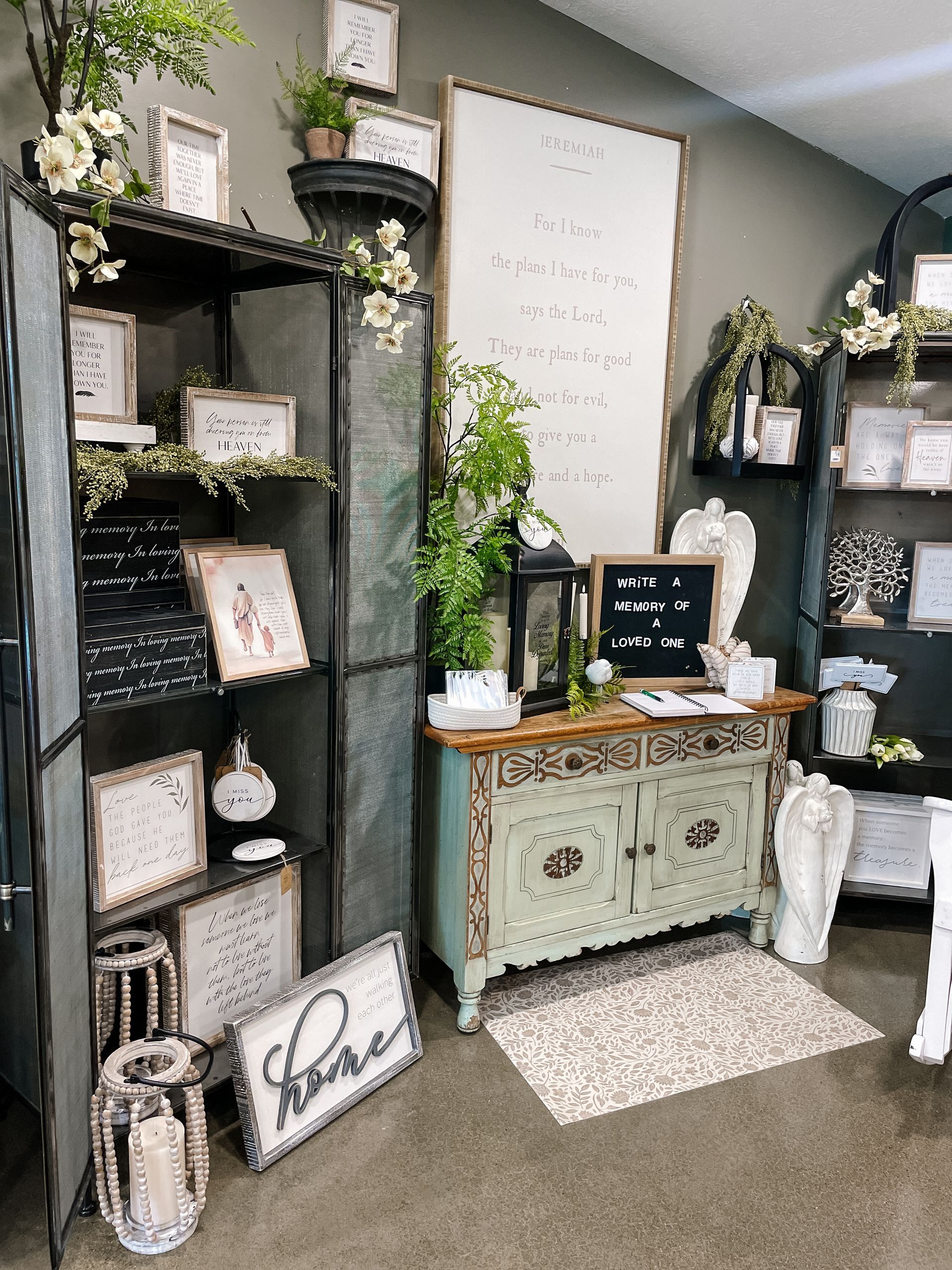 Interior shop display with decorative signs, furniture, and greenery.