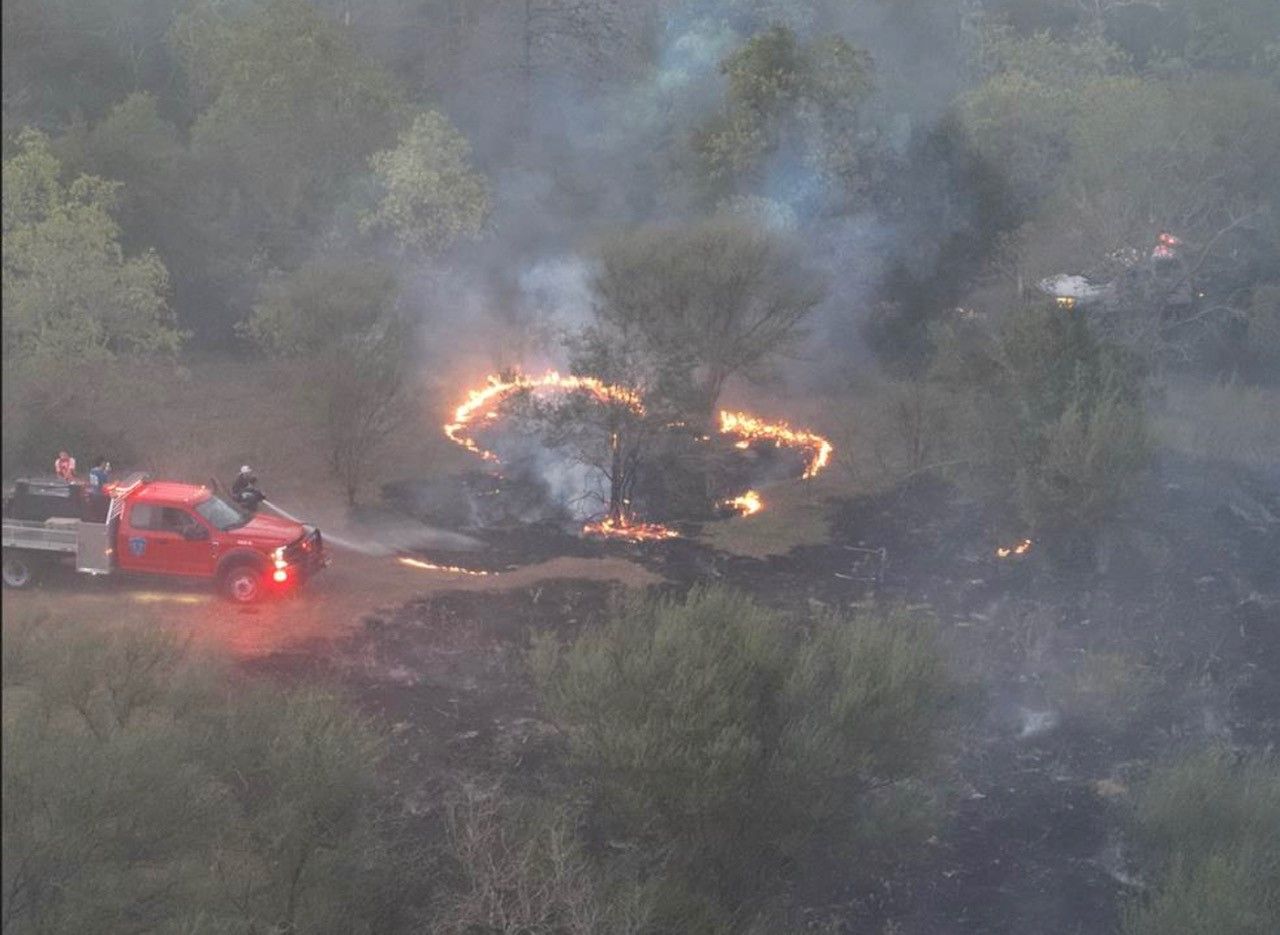 A red truck is parked in front of a forest fire