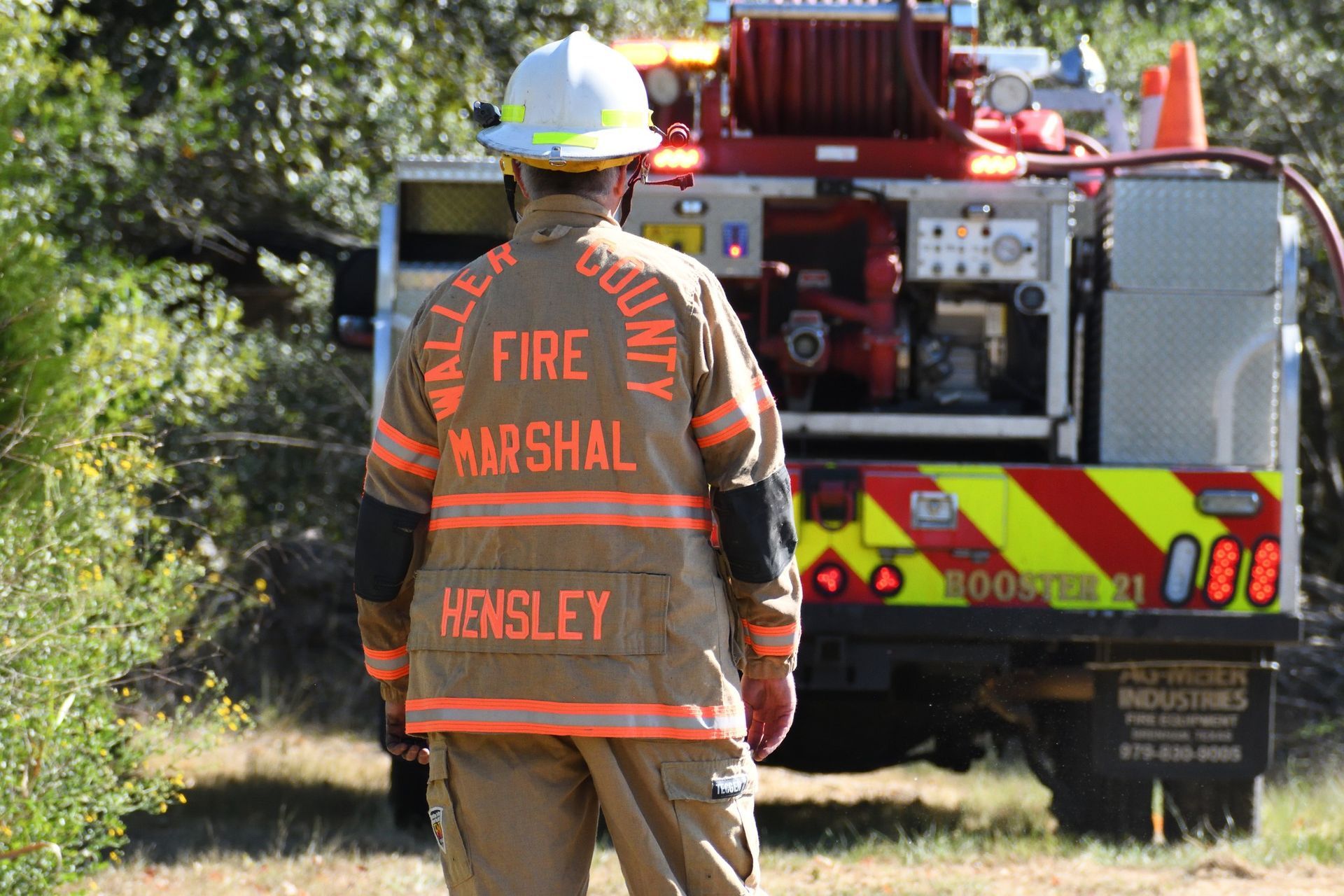 A Waller County Fire Marshal stands in front of the back of a fire booster truck in the background.