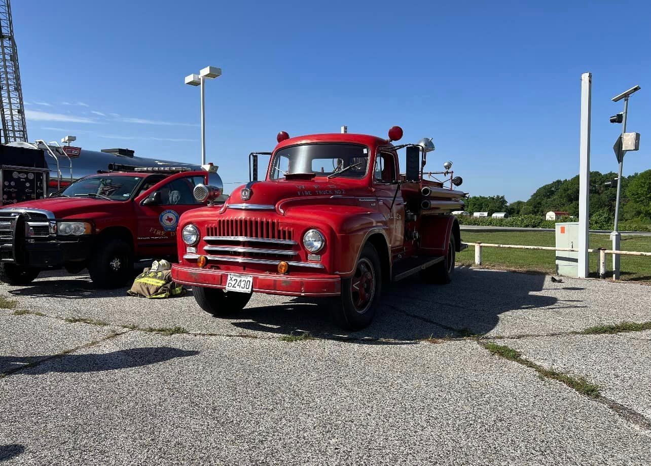 A red fire truck is parked in a gravel lot.
