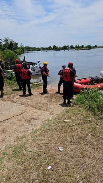 A group of people are standing next to a body of water.