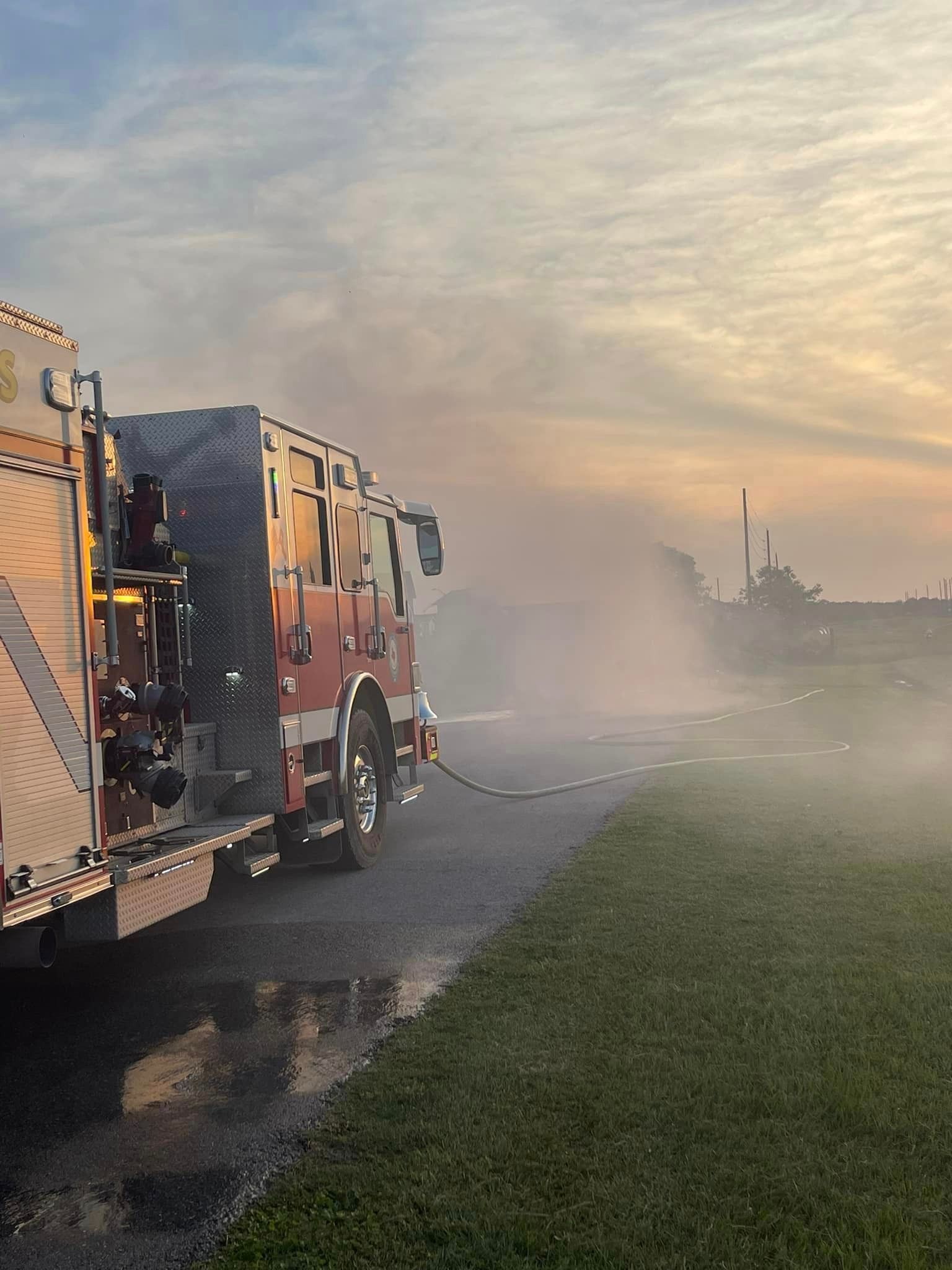 A fireman is using a hose to put out a fire in a dumpster.