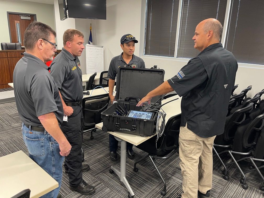 A group of men are standing around a table looking at a case.