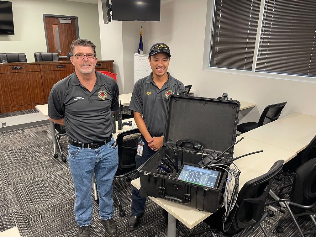 Two men are standing next to each other in a room holding a briefcase.