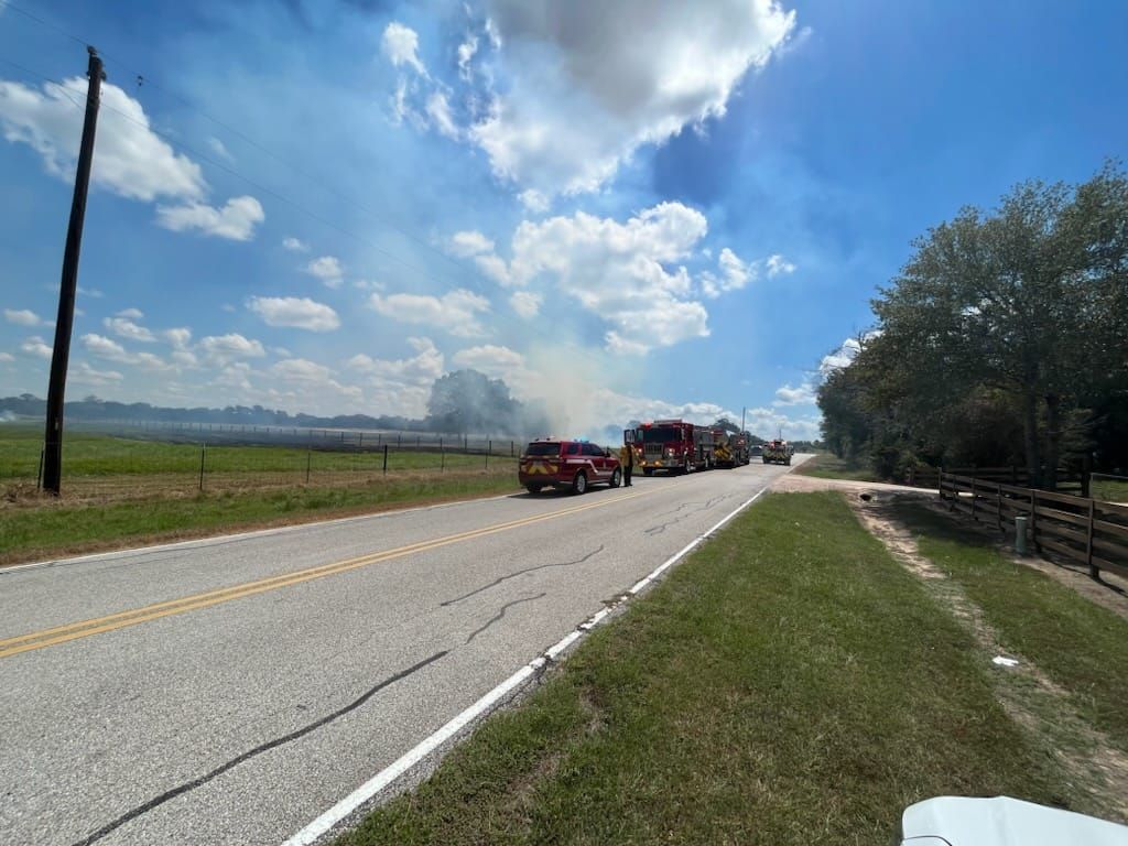 A row of fire trucks are parked on the side of a road.