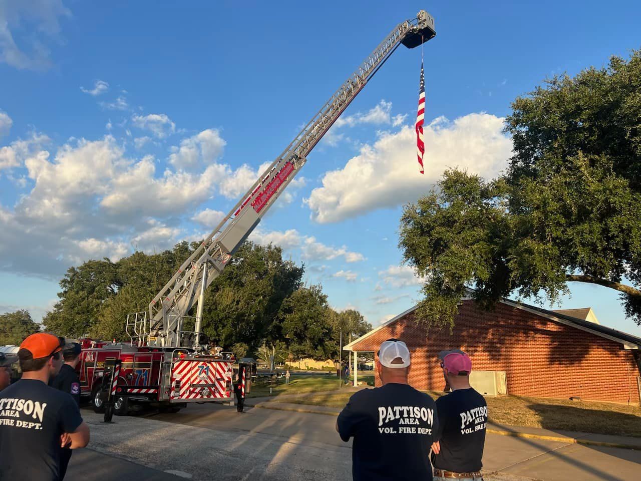 A Waller-Harris aerial truck holding an American flag parked in front of a church.