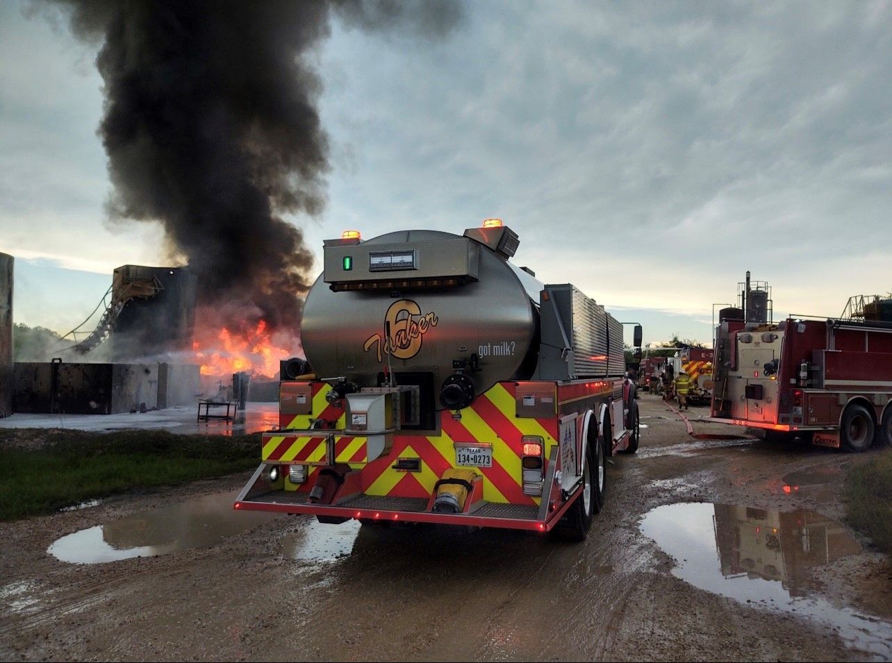 A fire truck is parked in front of a large fire.
