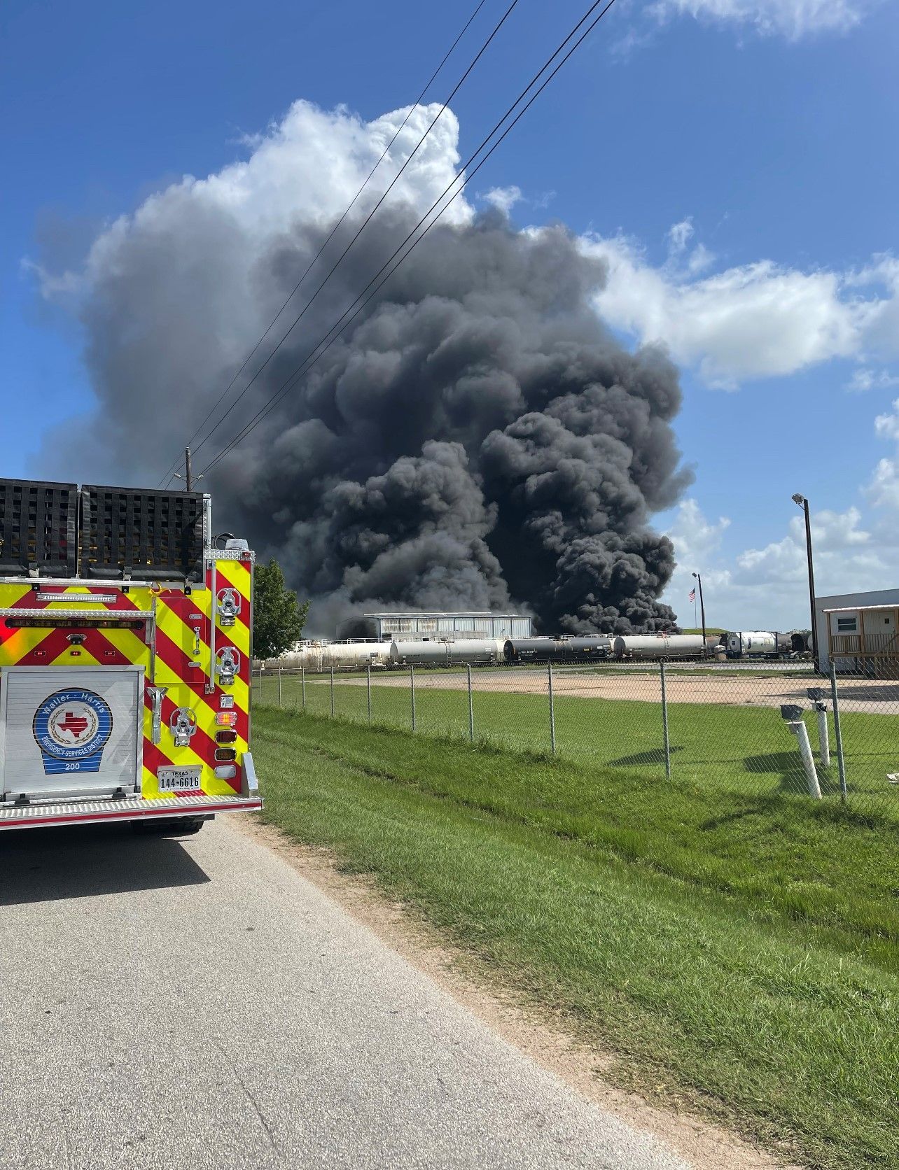 A fire truck is parked in front of a large cloud of smoke coming out of a building.