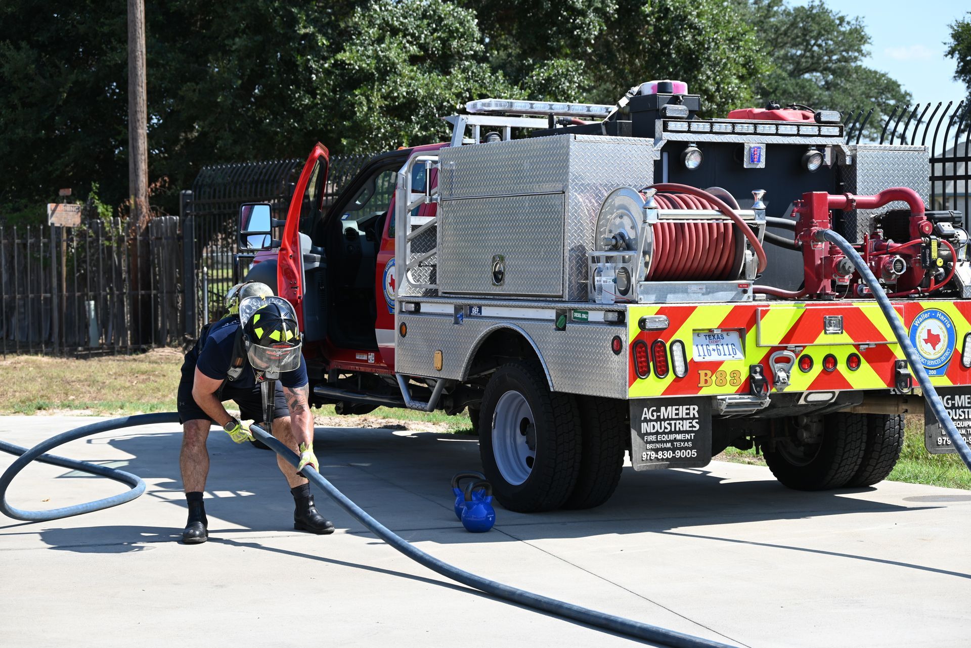 A firefighter is holding a hose in front of a fire truck.