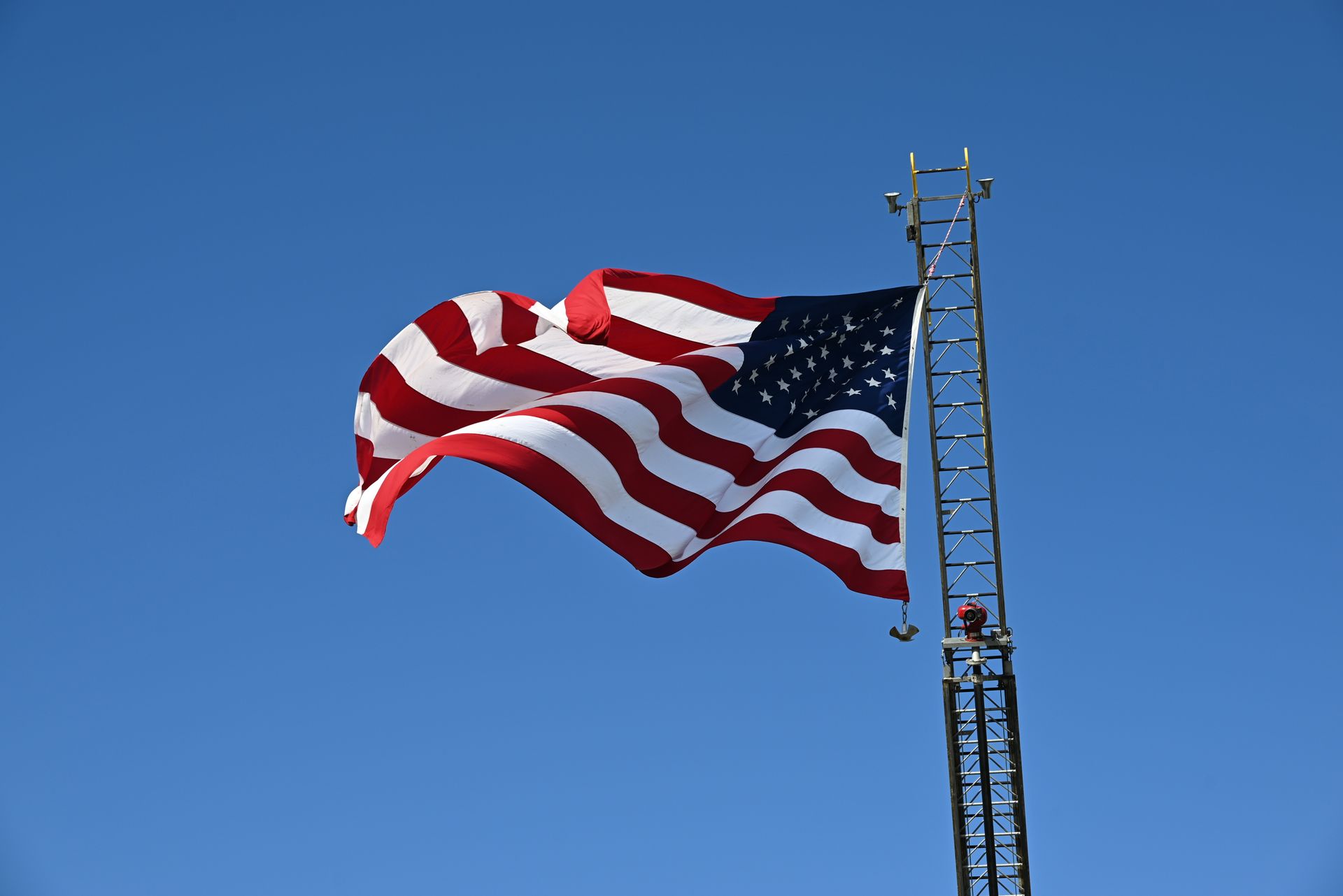 An american flag is waving in the wind against a blue sky