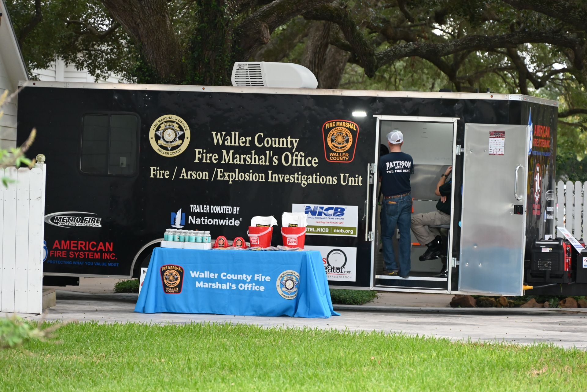 A Waller county fire marshal 's office trailer with a blue table in front of it at a festival.