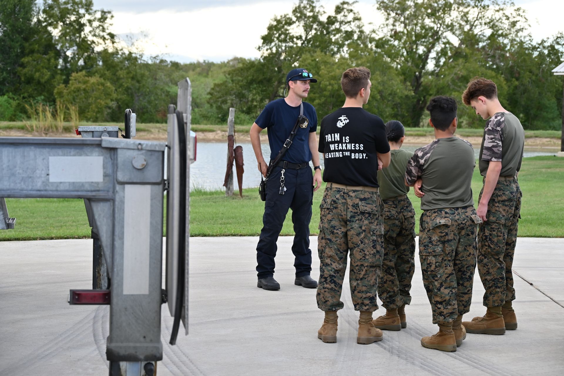 A group of young men in military uniforms are standing around a trailer