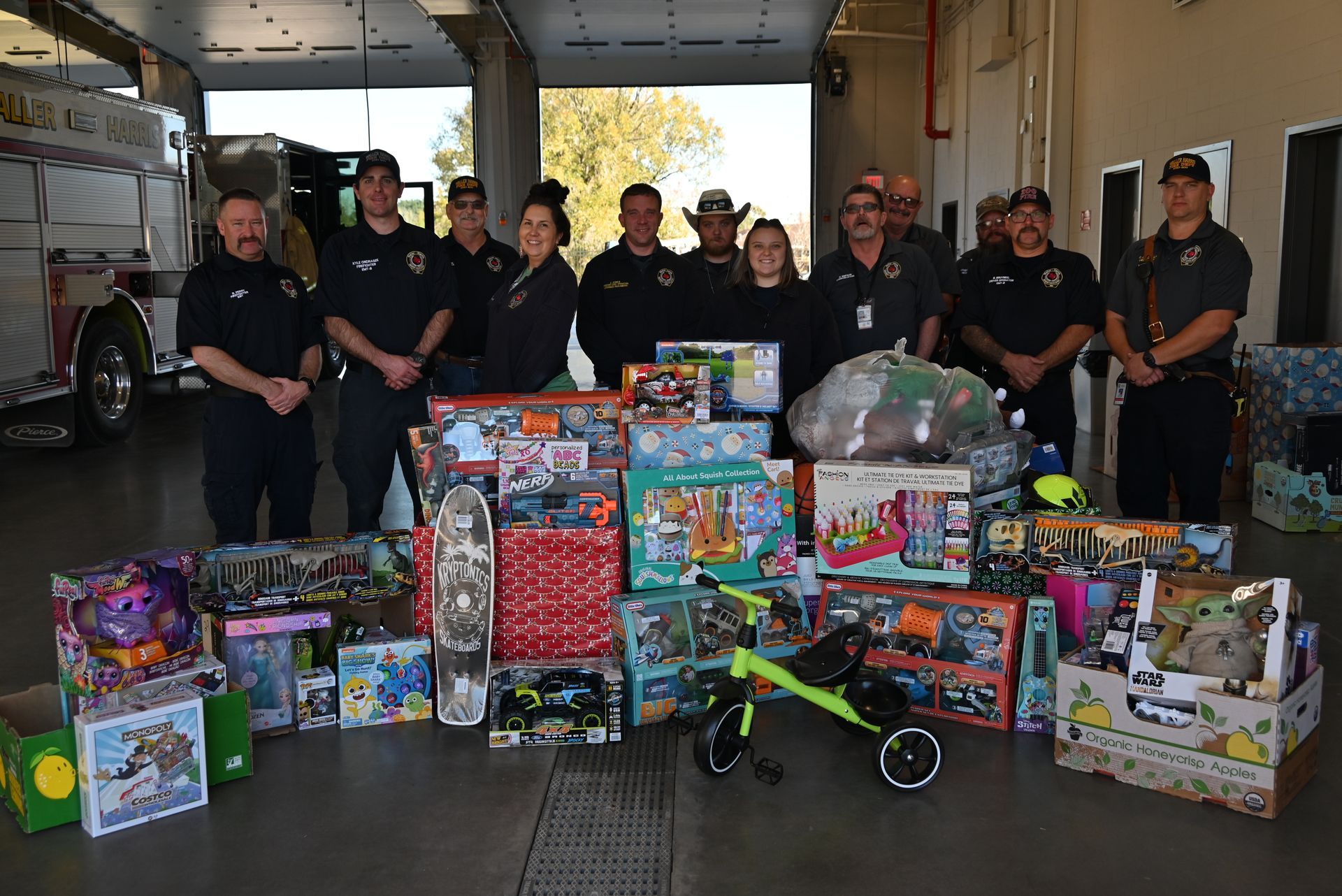 A group of firefighters are standing in front of a pile of toys.