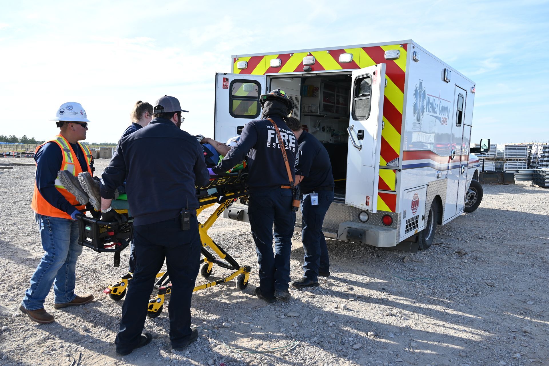 A group of paramedics are loading a patient into an ambulance.