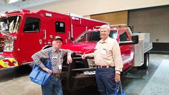 Two men are standing next to a red fire truck.