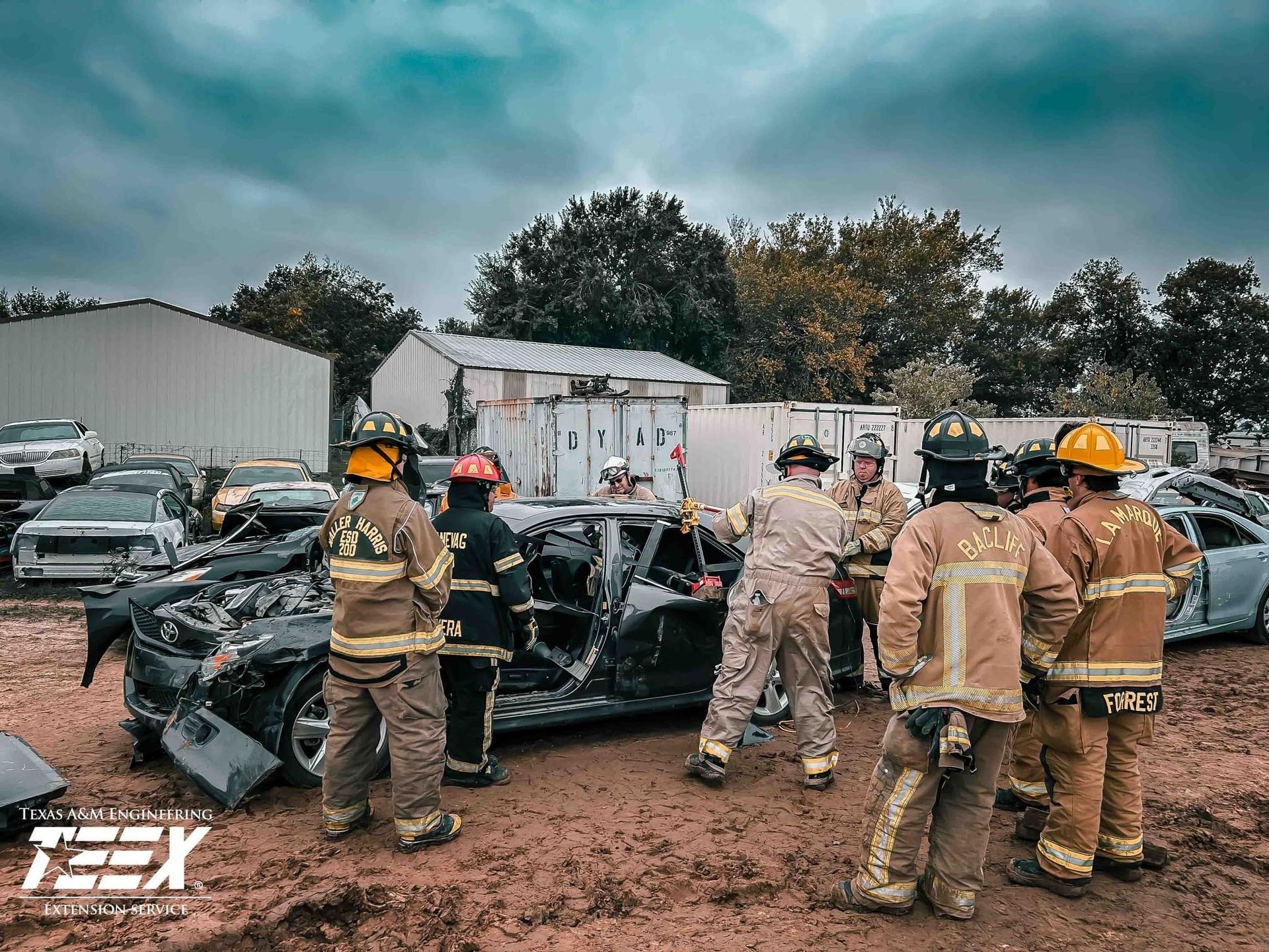 A group of firefighters are standing around a car during a training class at the Texas A&M Engineering Extension Service.