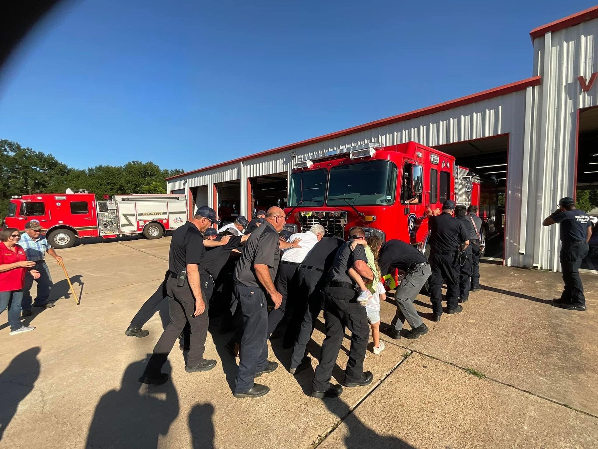 A group of firefighters are standing in front of a fire truck in a parking lot.